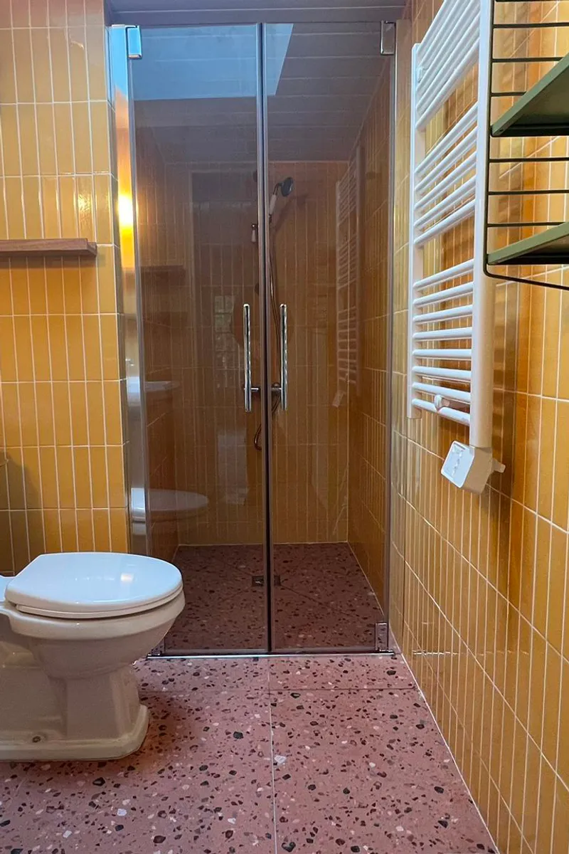 Rénovation de salle de bain à Concarneau avec carrelage vertical orange et sol en terrazzo terracotta