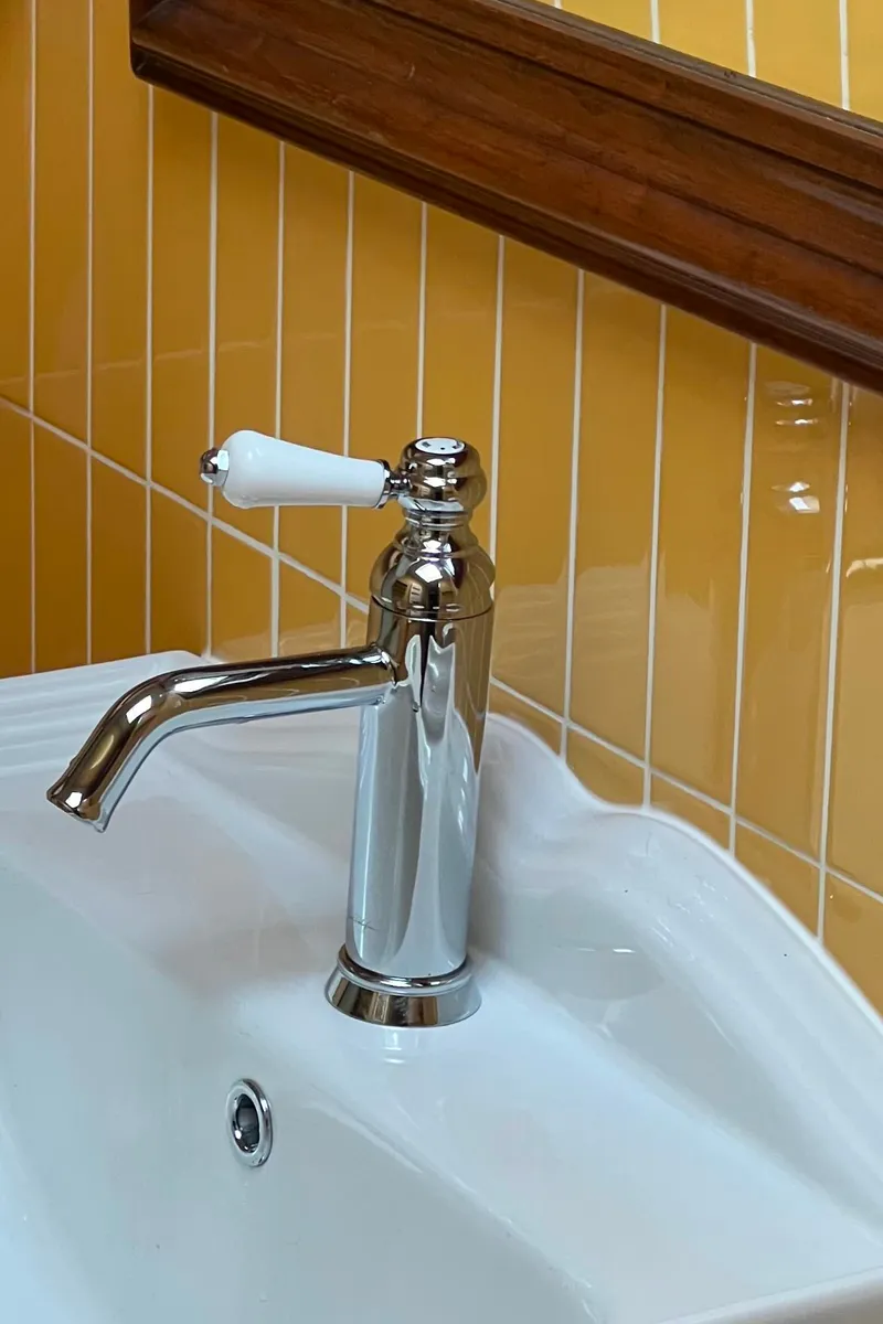 Robinetterie rétro chromée sur lavabo blanc et carrelage jaune moutarde pour une salle de bain à Concarneau