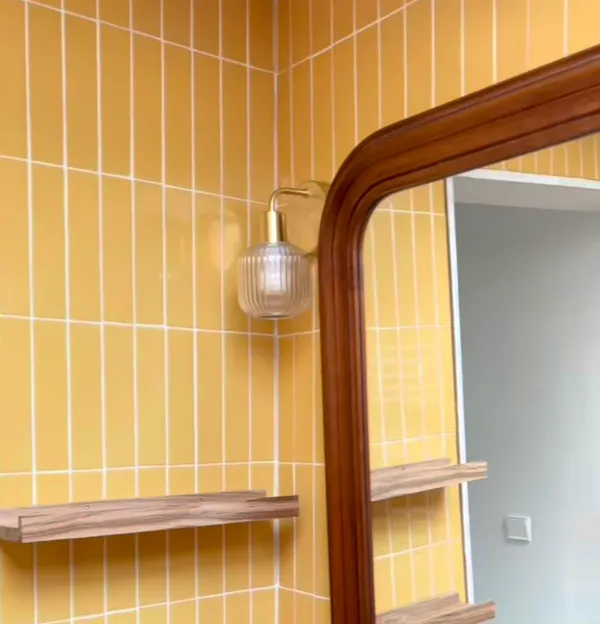 Miroir en bois et applique vintage en laiton sur carrelage jaune pour une salle de bain à Concarneau