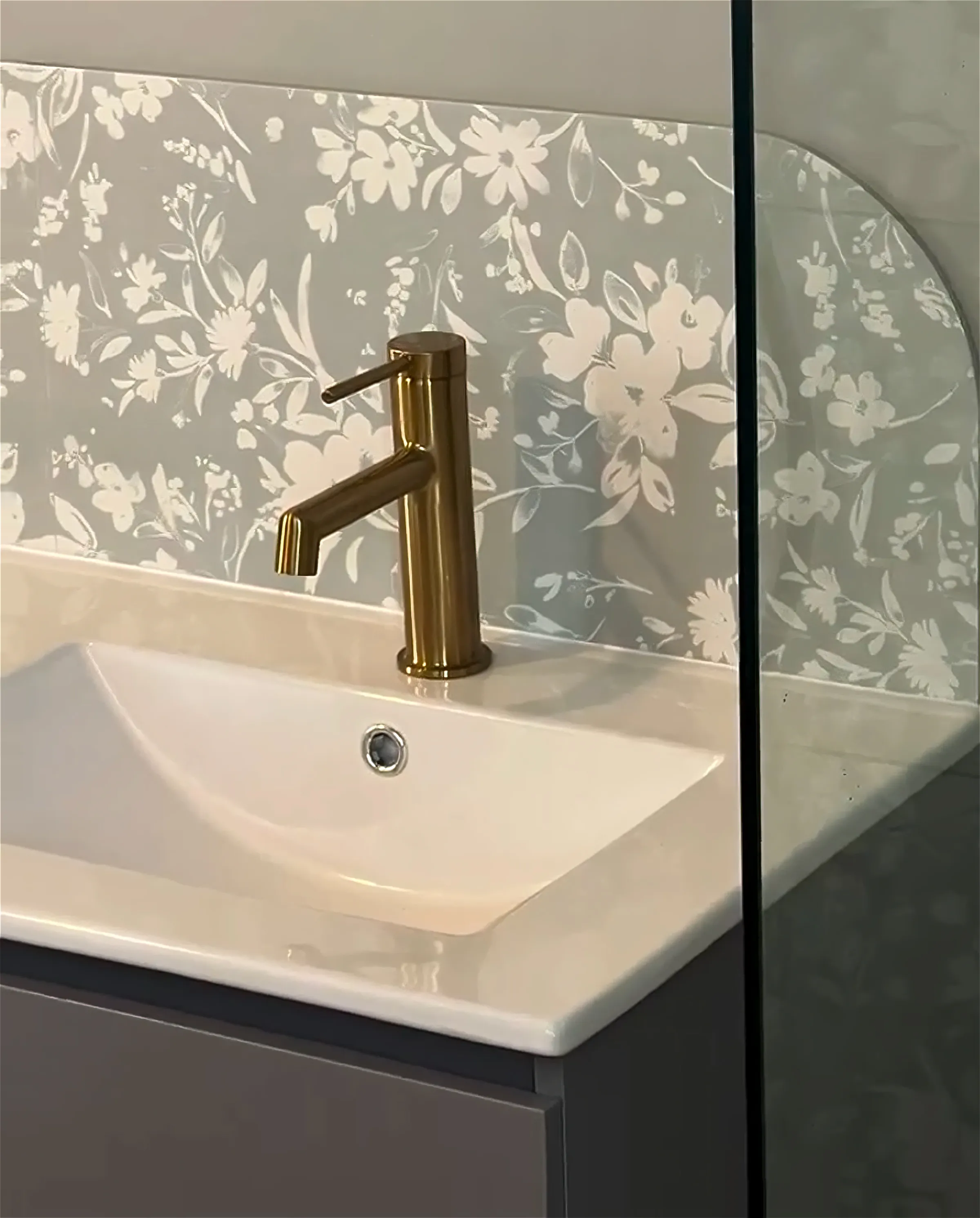 Robinetterie dorée et vasque blanche avec crédence fleurie pour une salle de bain à Concarneau