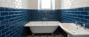 Rénovation de salle de bain à Quimper avec baignoire îlot, carrelage métro bleu et blanc et robinetterie rétro